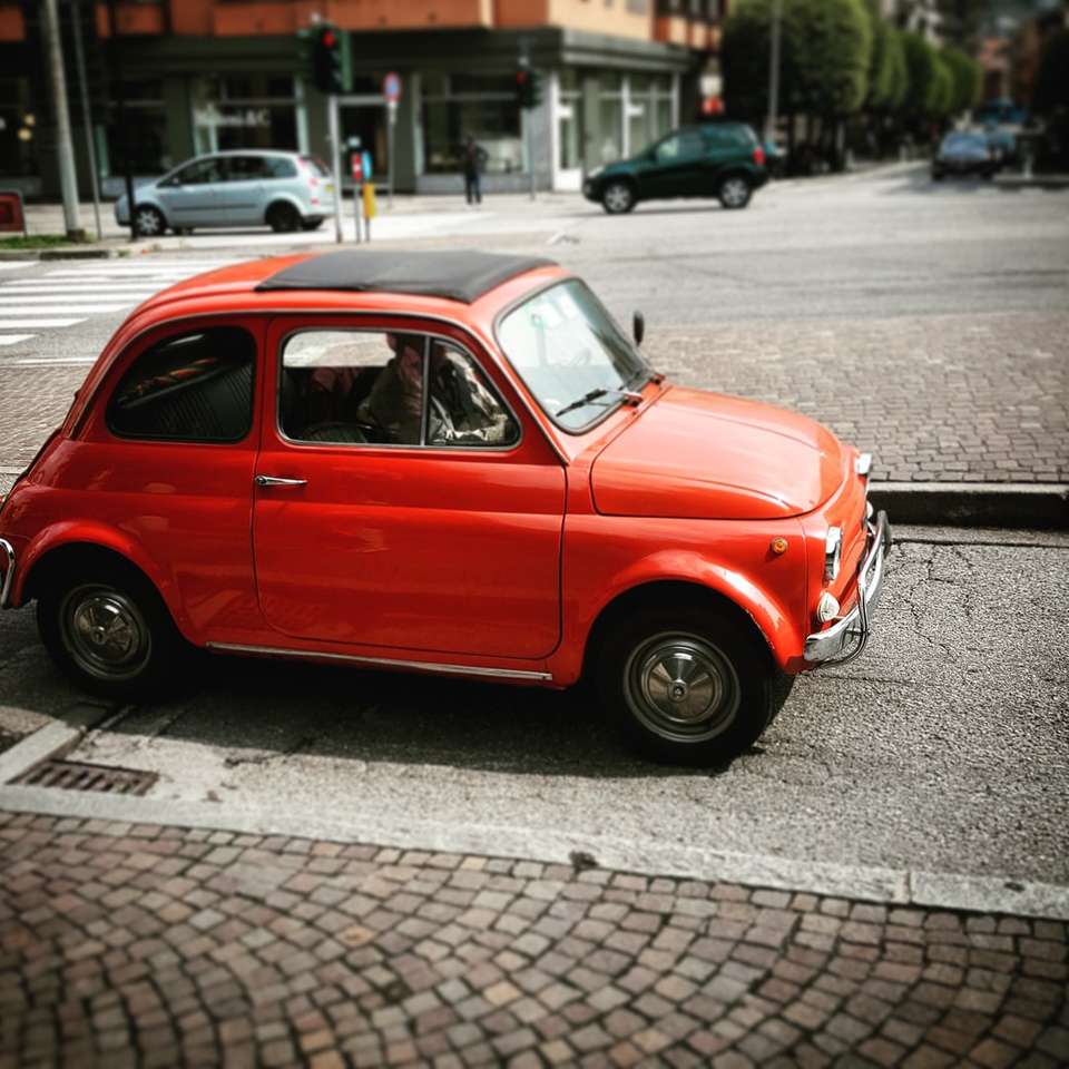 Scarabeo rosso Volkswagen parcheggiato sul marciapiede durante il giorno puzzle online