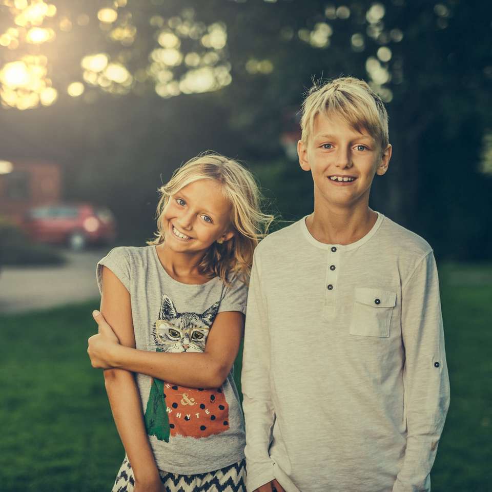 κορίτσι και αγόρι που στέκεται στο πράσινο γρασίδι πεδίο online παζλ