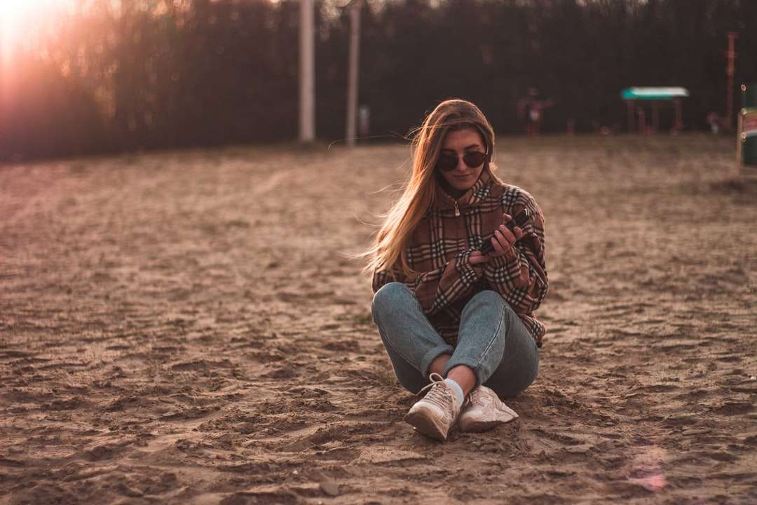 žena v modré džínové džíny sedí na hnědý písek online puzzle