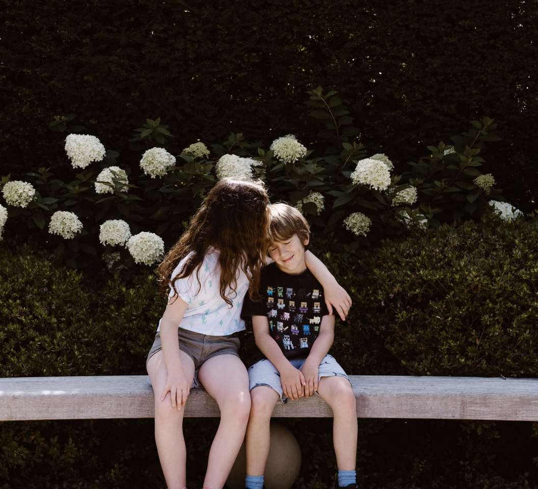Dos niñas y niños pequeños sentados en un banco de hormigón rompecabezas en línea