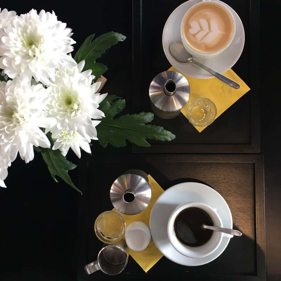чашка кави біля білих квітів онлайн пазл