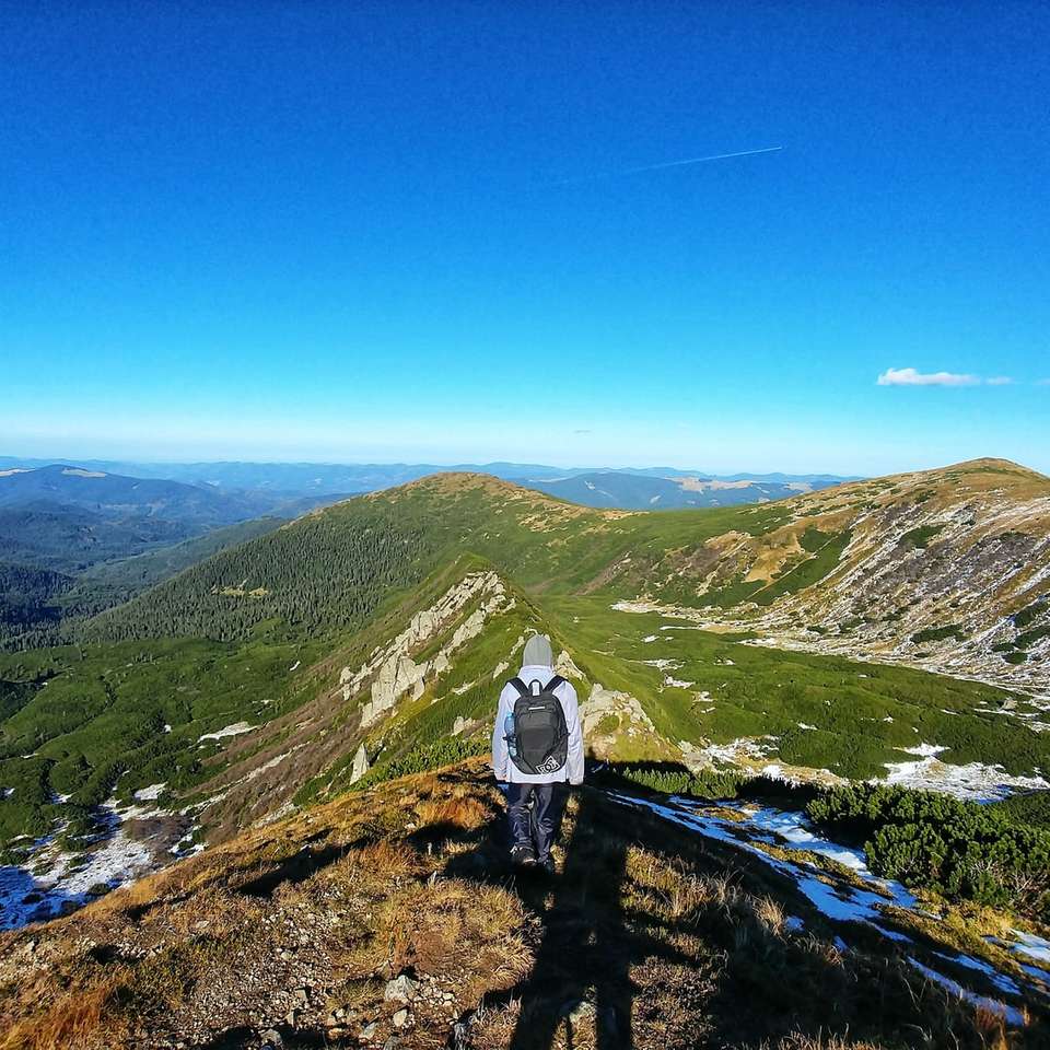 човек, стоящ на върха на планината с изглед към града онлайн пъзел