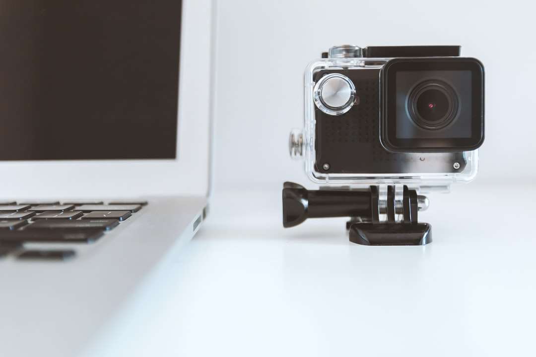Caméra d'action noire à côté d'un ordinateur portable blanc puzzle en ligne