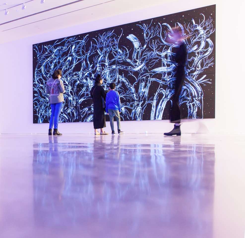 fyra personer som står framför abstrakt målning Pussel online