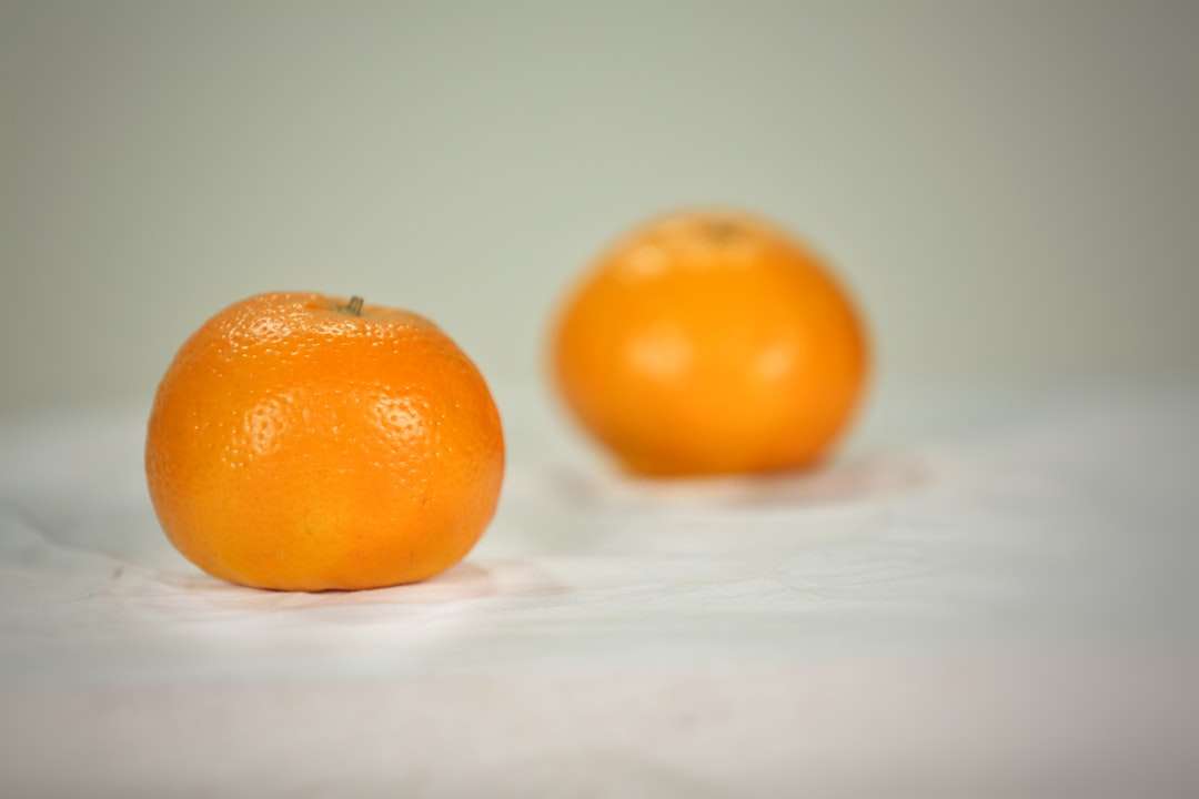 2 πορτοκαλί φρούτα σε λευκό κλωστοϋφαντουργικό προϊόν online παζλ