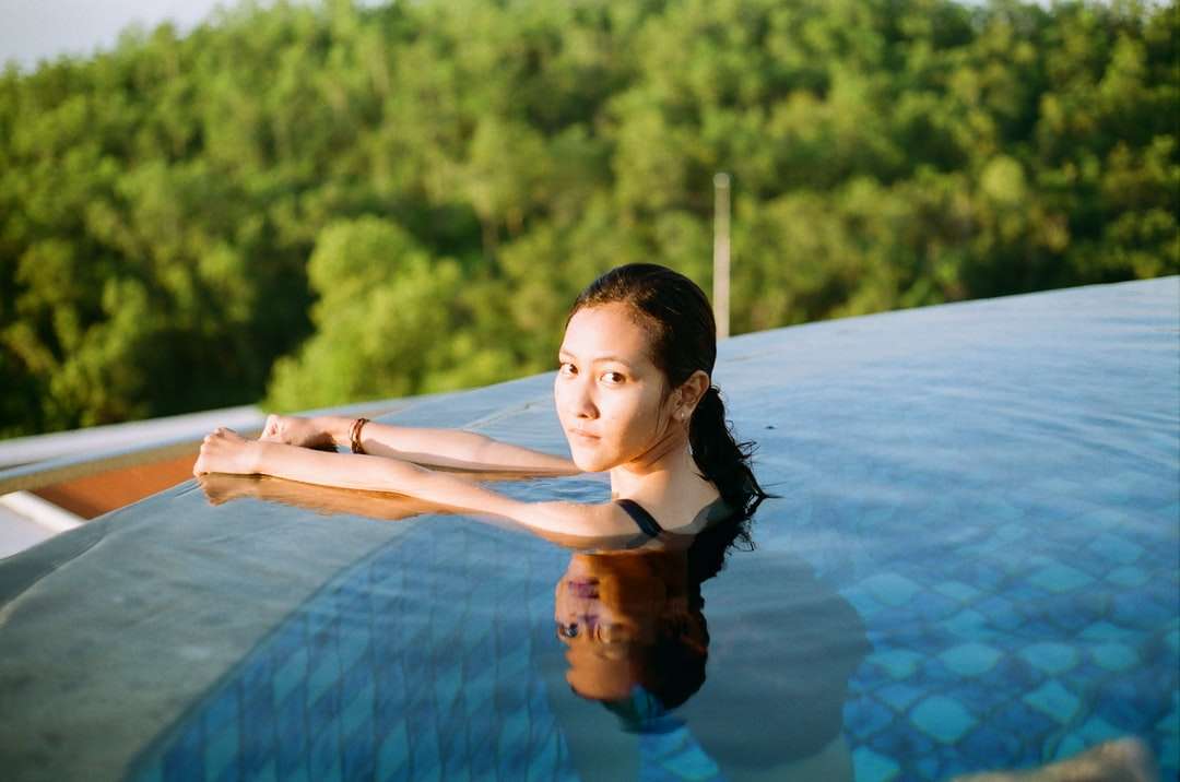 vrouw in blauw en zwart mouwloos onderhemd op zwembad online puzzel