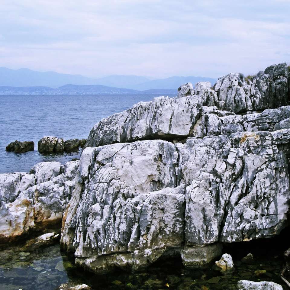 graue Felsformation in der Nähe von Gewässern während des Tages Online-Puzzle