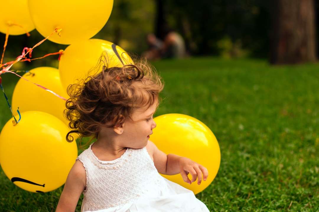 flickasammanträde på gräs nära ballongen Pussel online