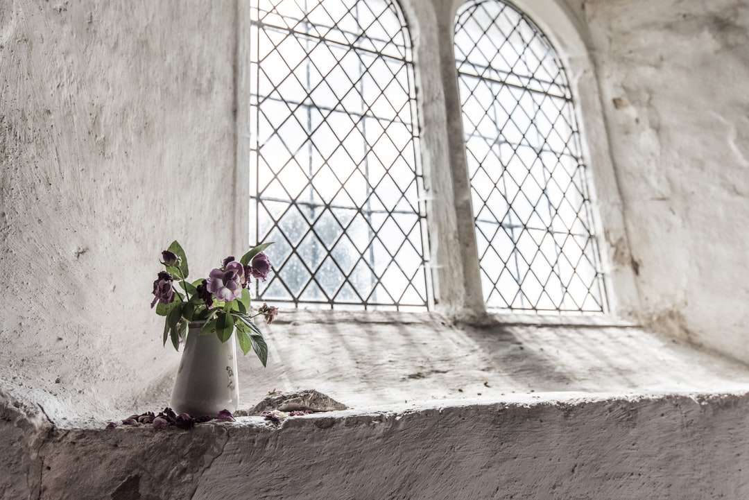 зеленые и фиолетовые цветы лепестков на белой вазе возле окна пазл онлайн