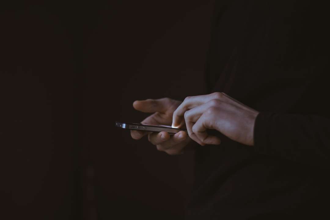 silhuettfoto av personen som håller smartphonen Pussel online