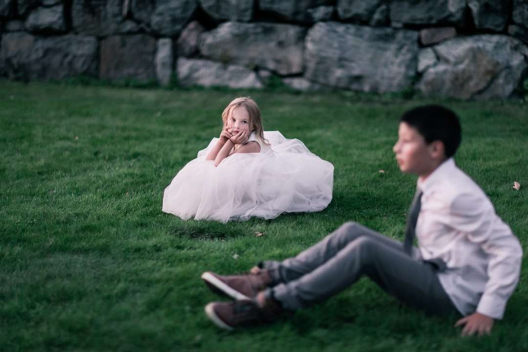 дівчина сидить на зеленій траві, дивлячись на хлопчика пазл онлайн