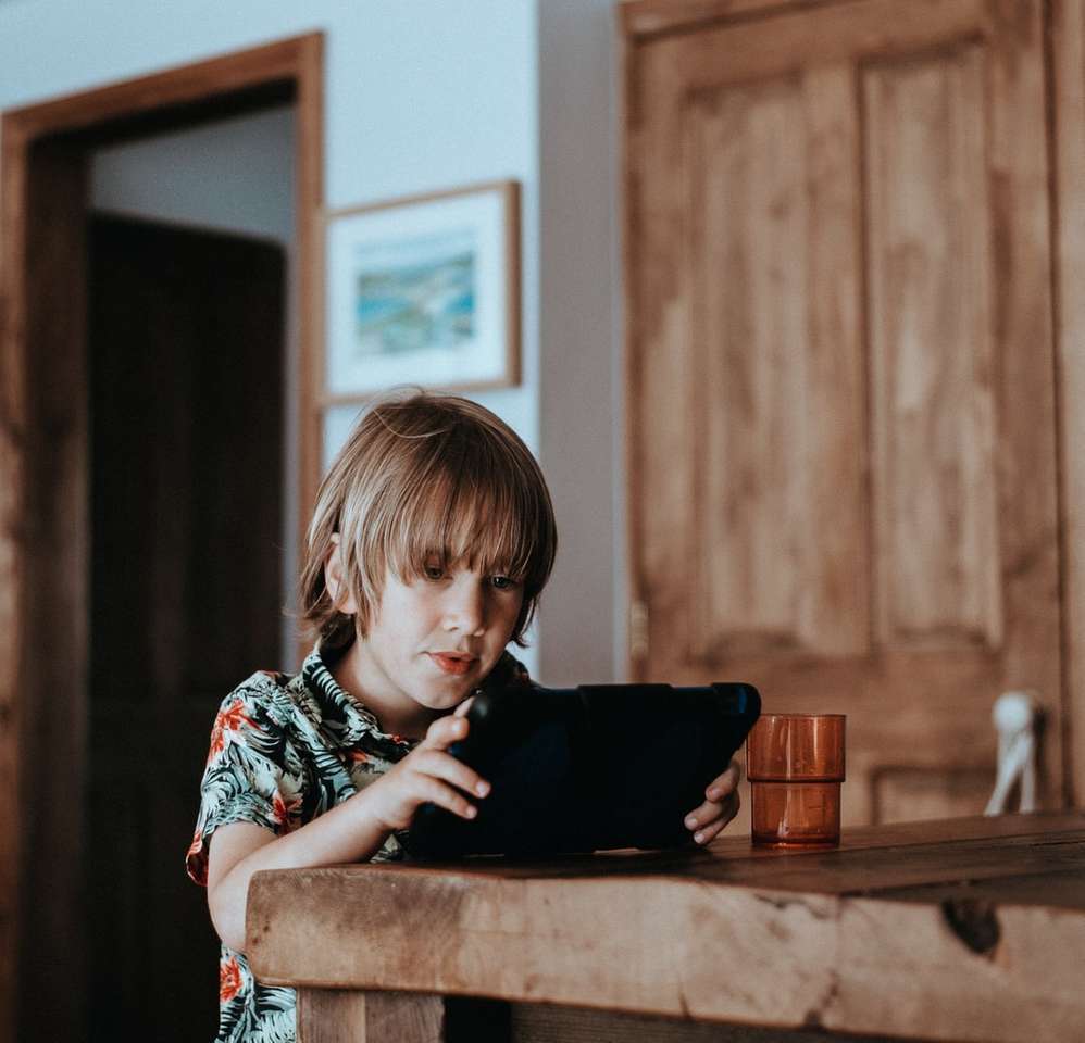 selective focus of child using tablet computer on table jigsaw puzzle online