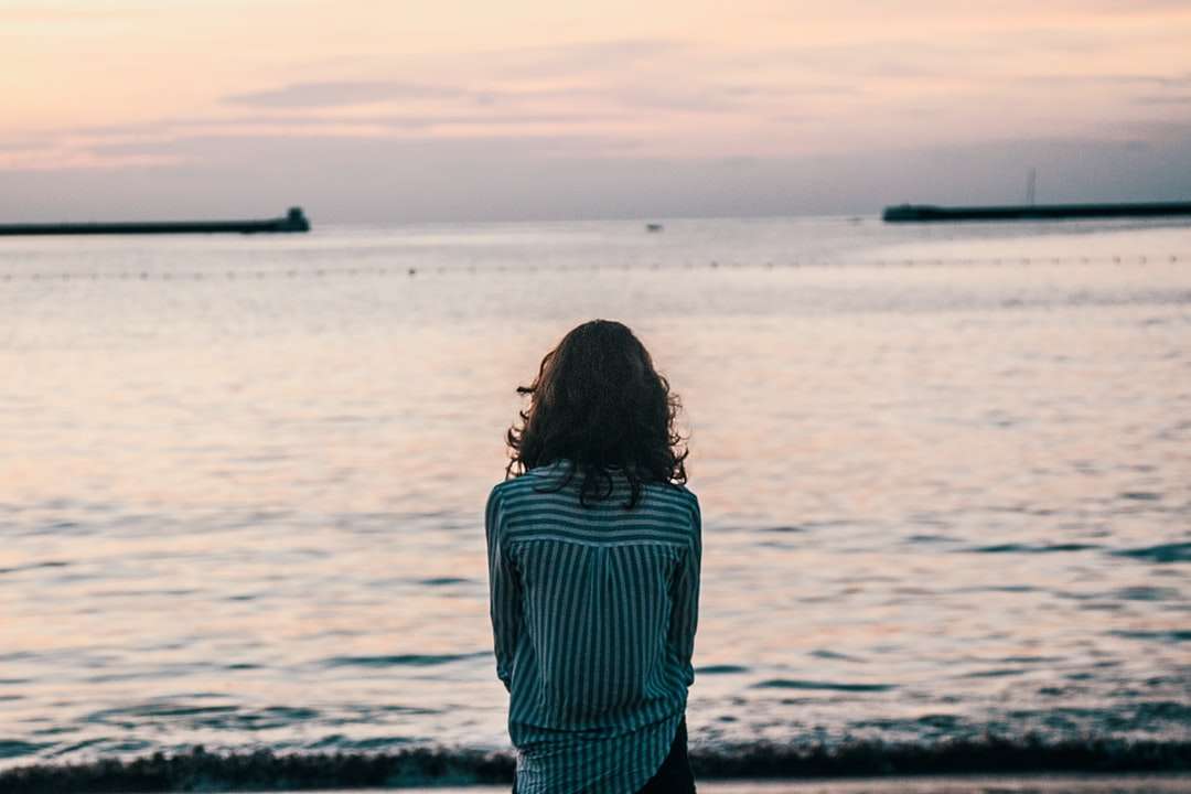 mulher na frente do oceano água sob o céu branco quebra-cabeças online