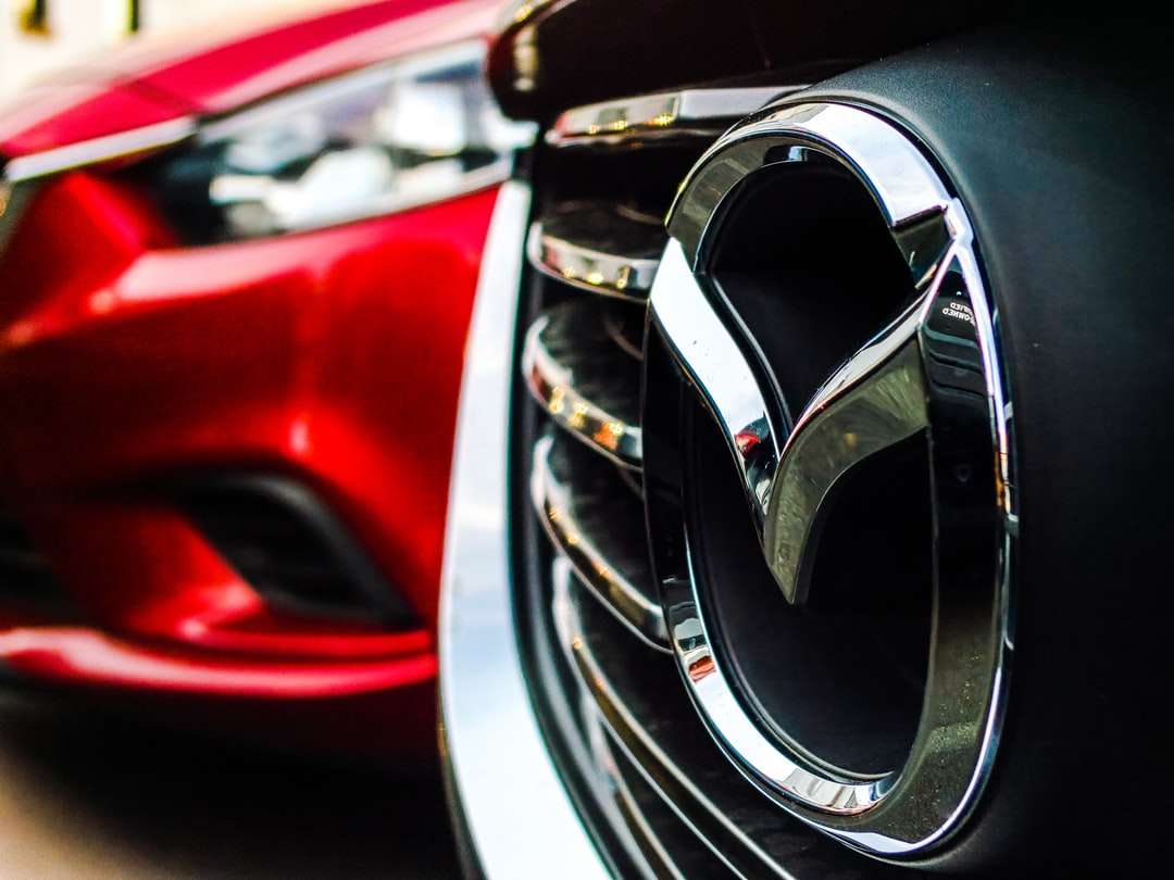 Έμβλημα Mazda στη μάσκα εκτός από το παρκαρισμένο κόκκινο αυτοκίνητο online παζλ