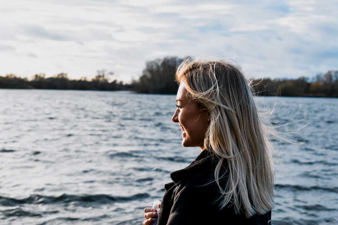 水域の近くに立っている黒いジャケットの女性 ジグソーパズルオンライン