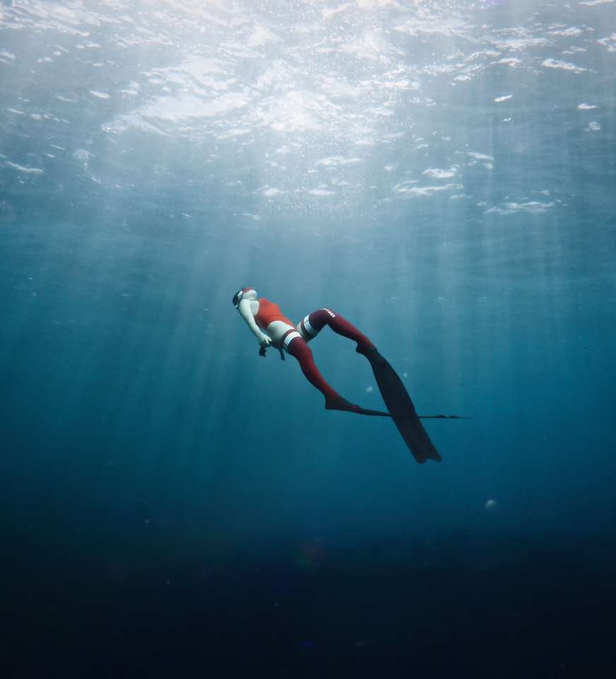 kvinna i vit och svart bikini som simmar i havet Pussel online