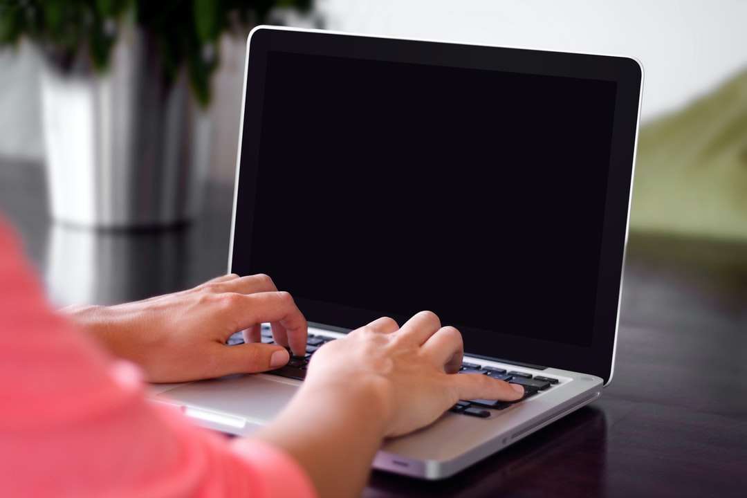 persoană care poartă cămașă roz tastând pe laptopul gri puzzle online