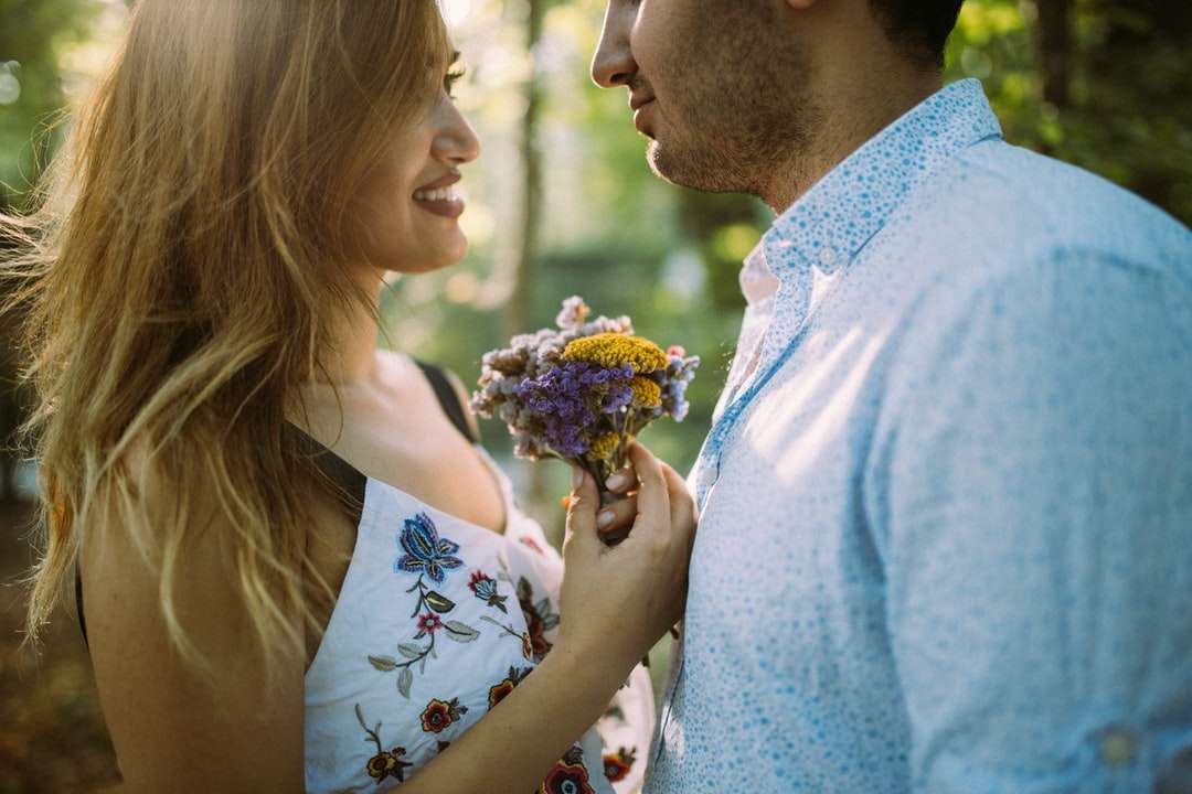hombre y mujer uno frente al otro mientras sostienen flores rompecabezas en línea