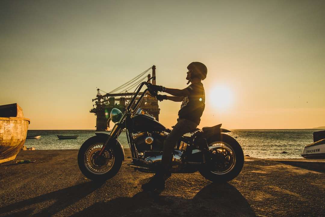Hombre en motocicleta en la playa durante la puesta de sol rompecabezas en línea