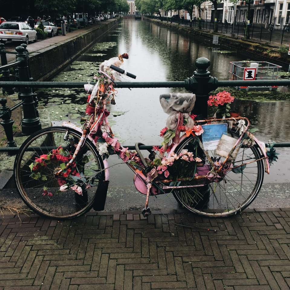 Bicicleta cubierta de flores en el puente cerca del estanque rompecabezas en línea