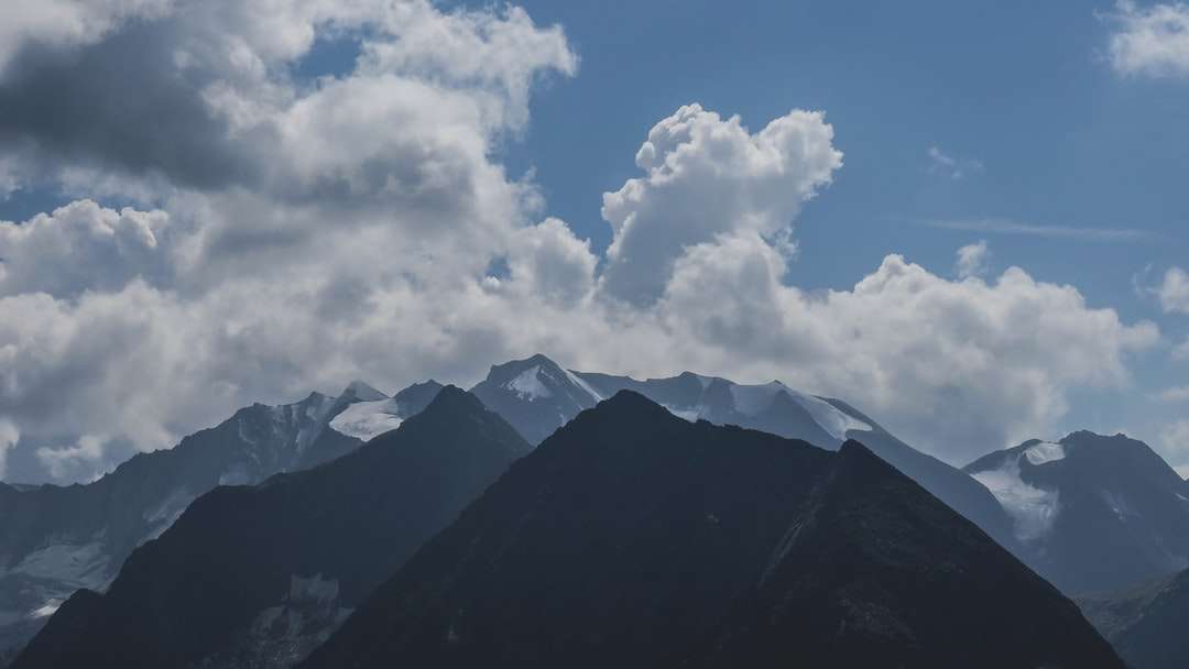 zelené a černé hory pod bílými mraky a modrou oblohou online puzzle