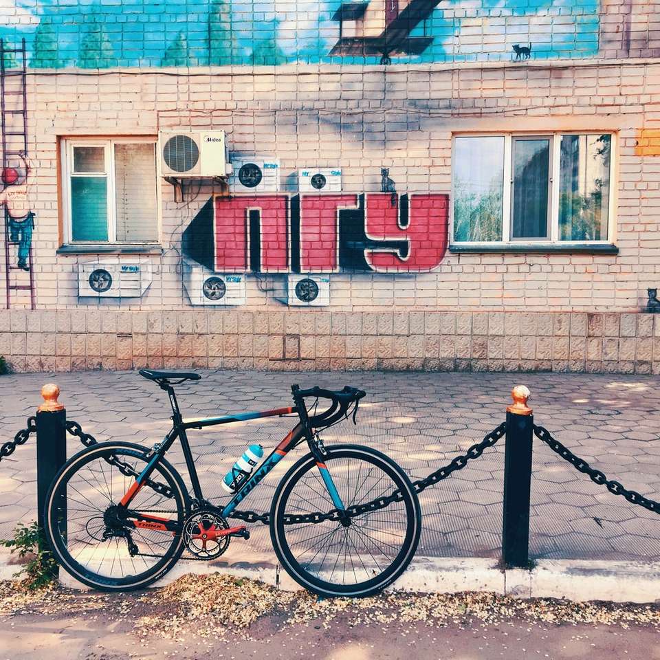 черен велосипед, паркиран до синьо-бяла бетонна сграда онлайн пъзел