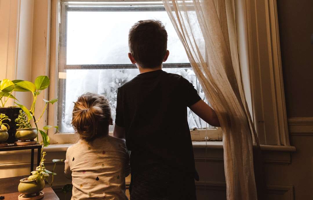 menino e menina em pé perto da janela, olhando para fora puzzle online