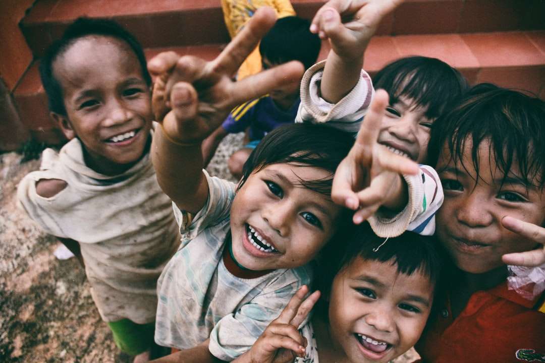 cinco niños sonriendo mientras hacen el signo de la mano de la paz rompecabezas en línea