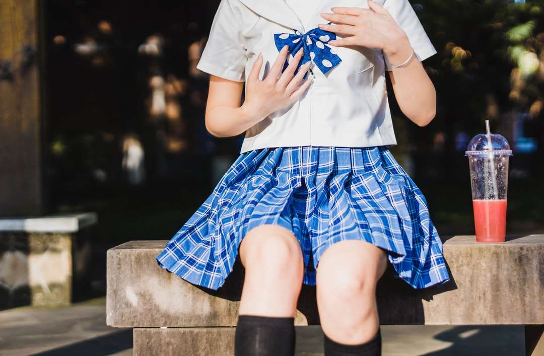 pessoa em uniforme escolar branco e azul sentada na praia quebra-cabeças online