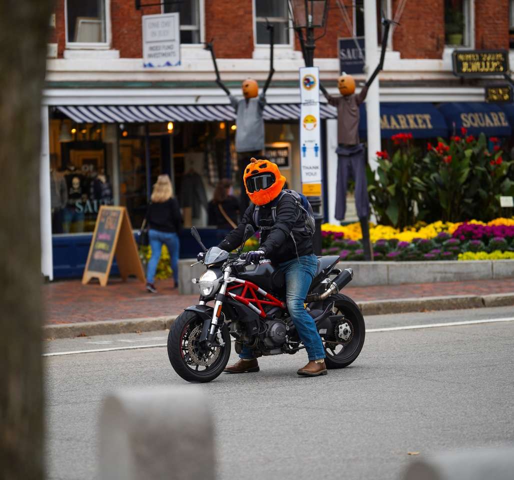 Mann im orangefarbenen Helm, der schwarzes Motorrad auf Straße fährt Online-Puzzle