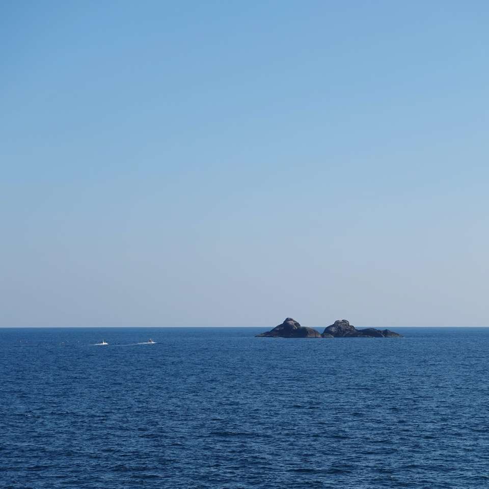 Dos barcos en el agua cerca del islote durante el día. rompecabezas en línea