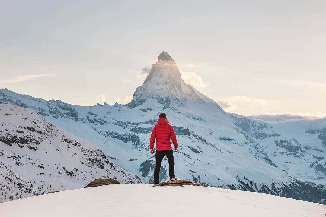 човек в червен качулка, стоящ на снежна планина онлайн пъзел