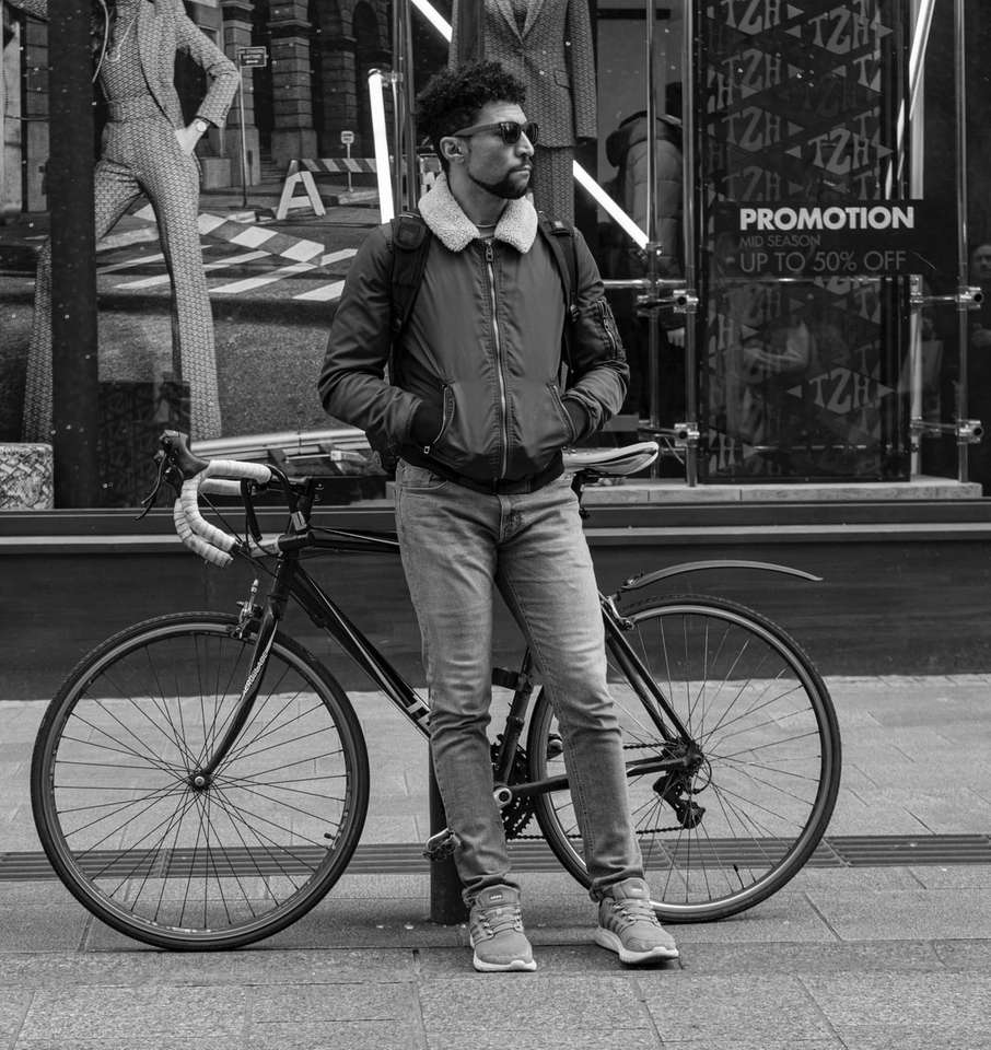 Hombre apoyado en balizas cerca de bicicleta rompecabezas en línea