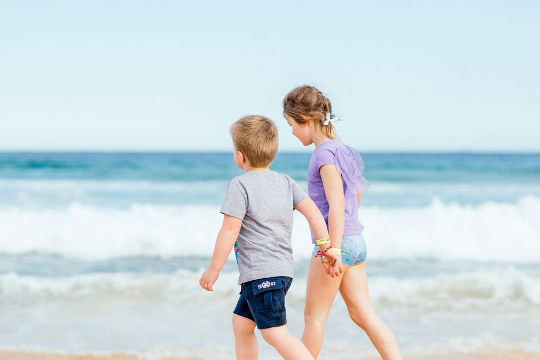 pojke i vit t-shirt och blå shorts som står på stranden pussel på nätet