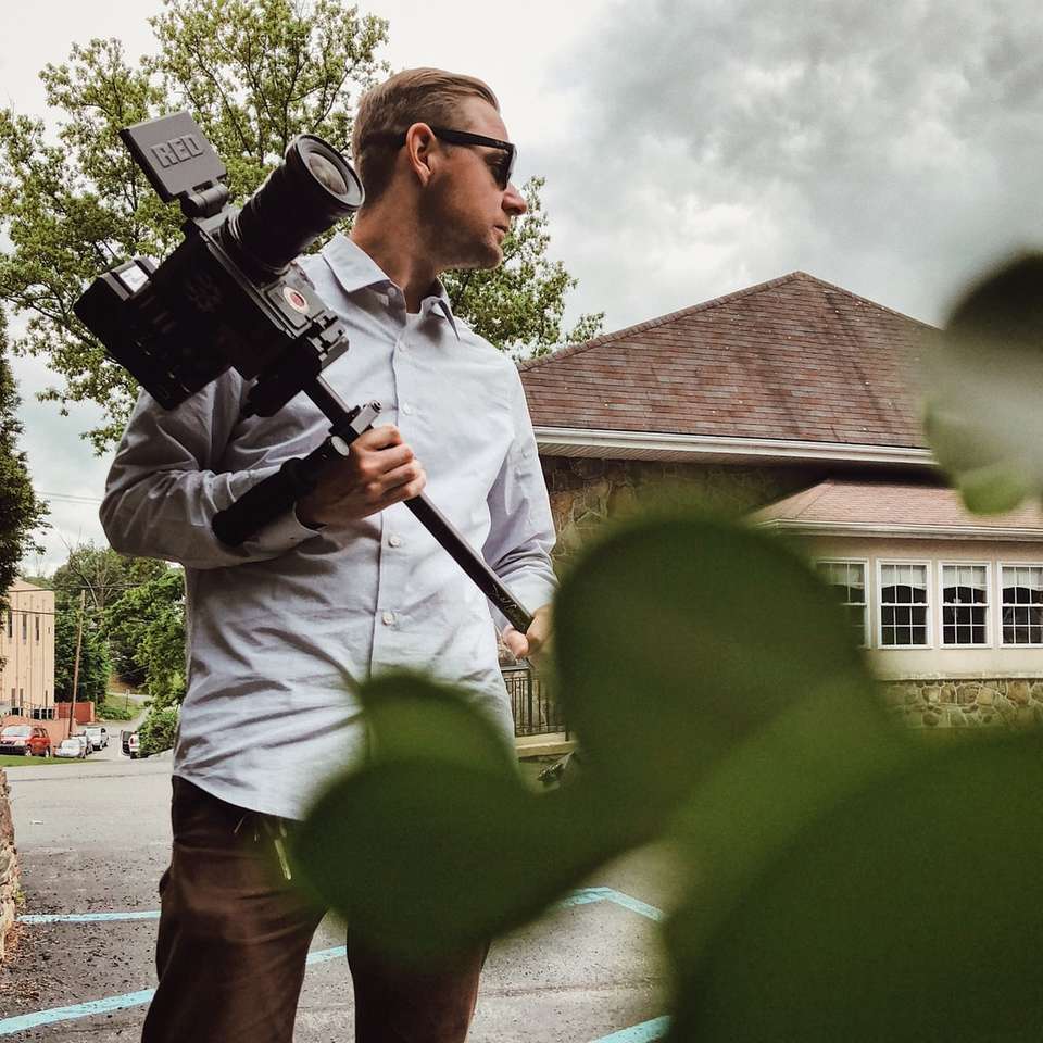 мужчина в серой классической рубашке держит камеру онлайн-пазл