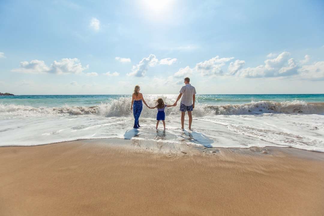 мъж, жена и дете, хванати за ръце на морския бряг онлайн пъзел