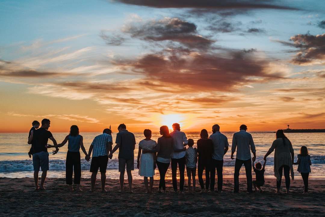 άνθρωποι που στέκονται στην ακτή κατά τη διάρκεια της χρυσής ώρας online παζλ