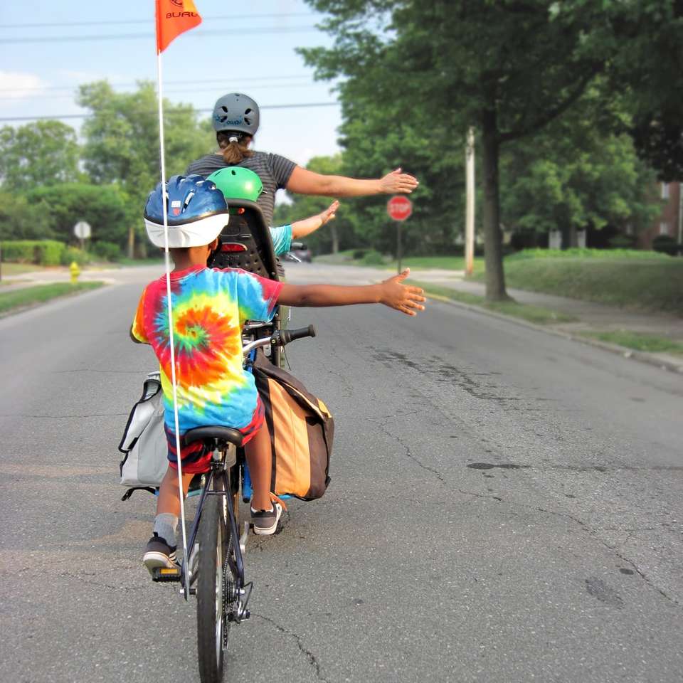 mulher de vestido azul e vermelho andando de bicicleta na estrada quebra-cabeças online