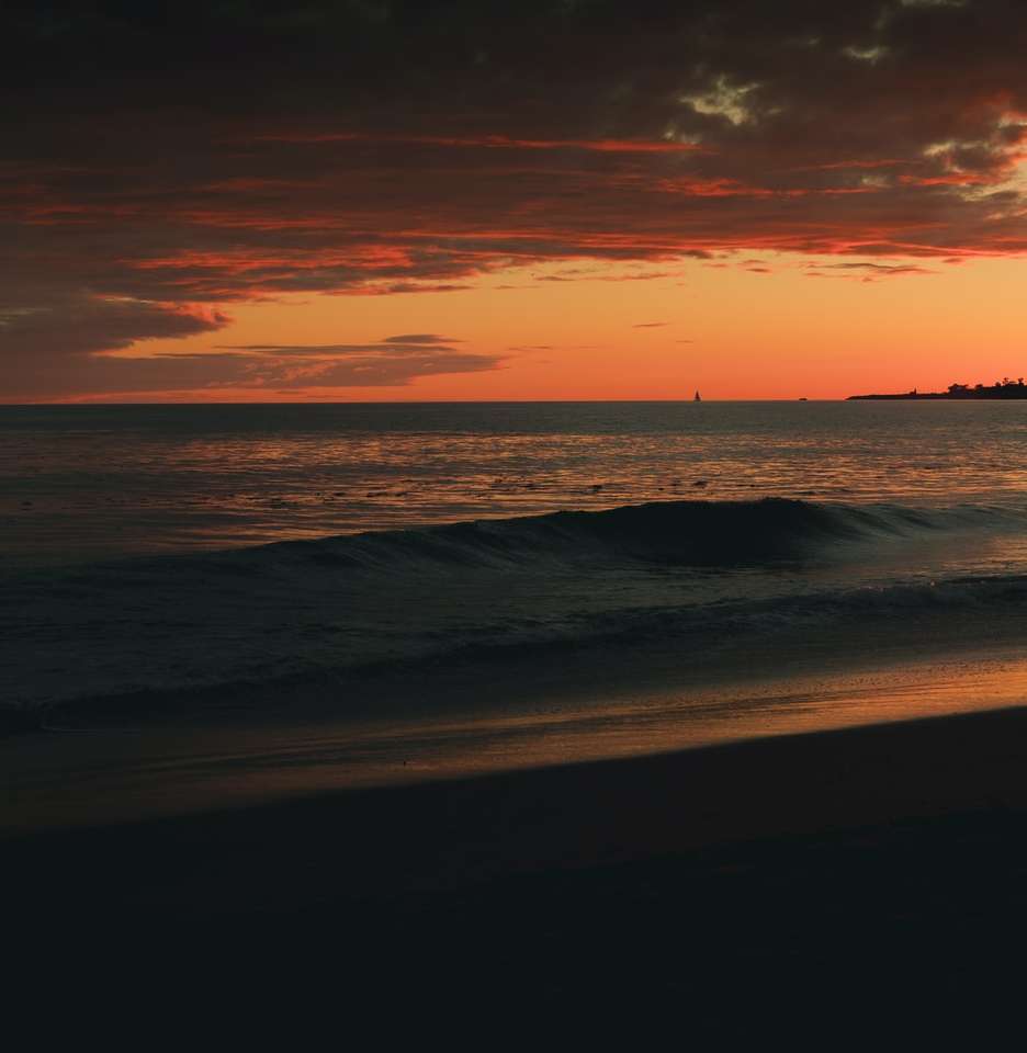 havsvågor som kraschar på stranden under solnedgången pussel på nätet