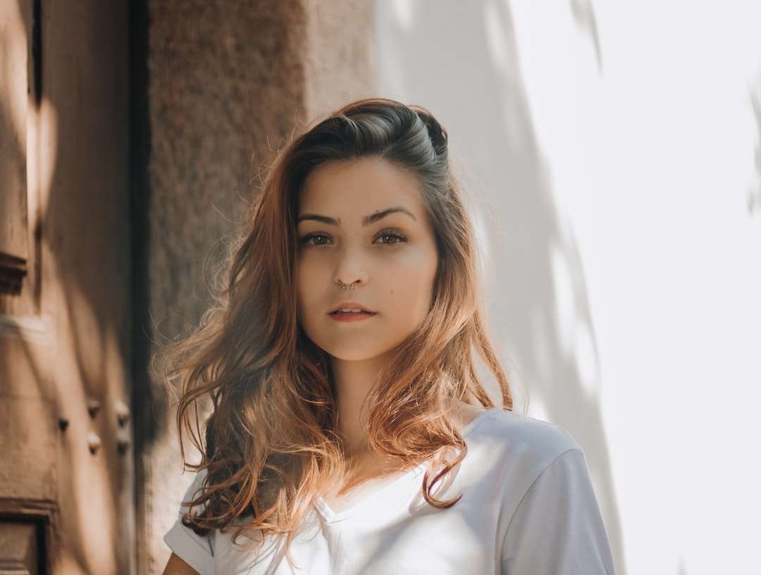женщина в белой рубашке опирается на коричневую бетонную стену пазл онлайн