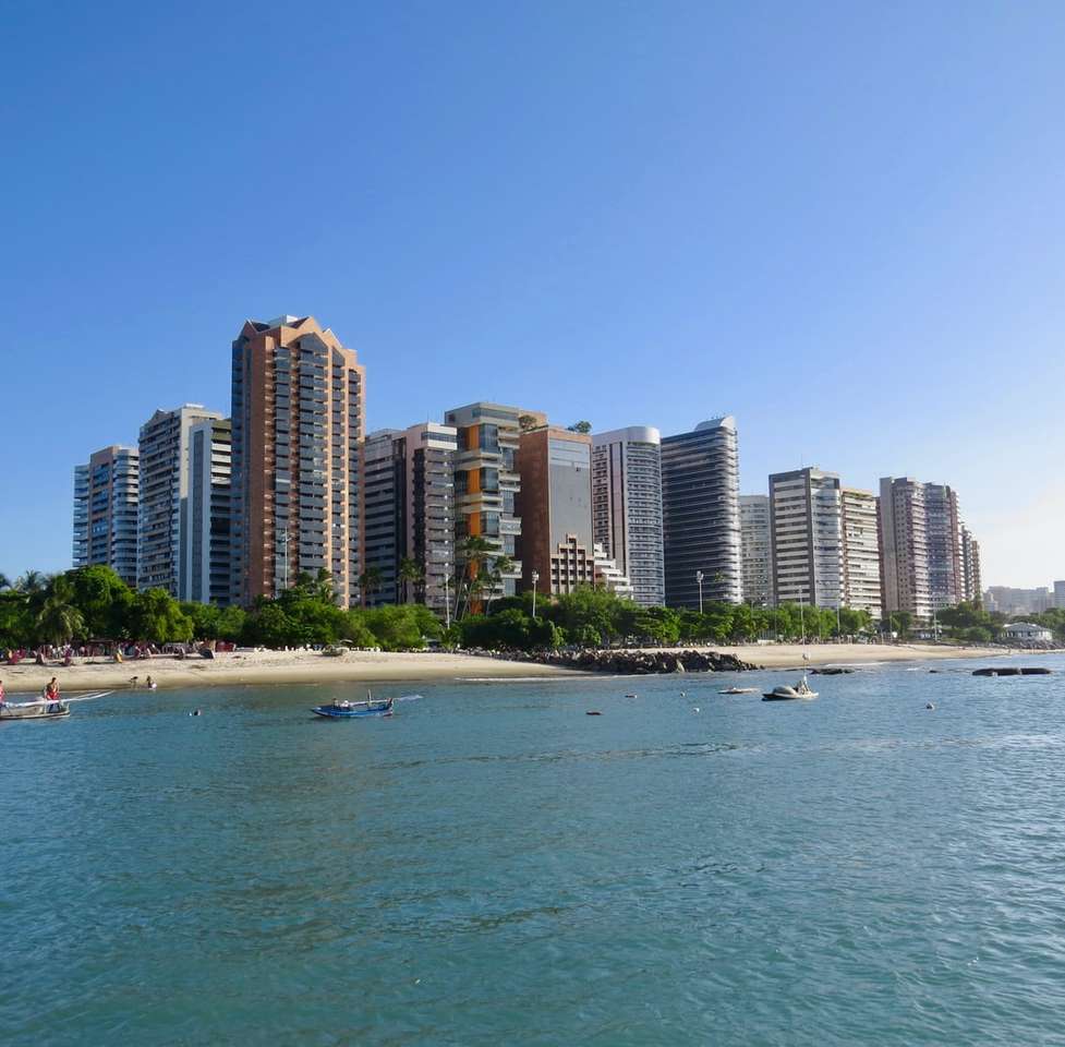 městské budovy u moře pod modrou oblohou během dne skládačky online