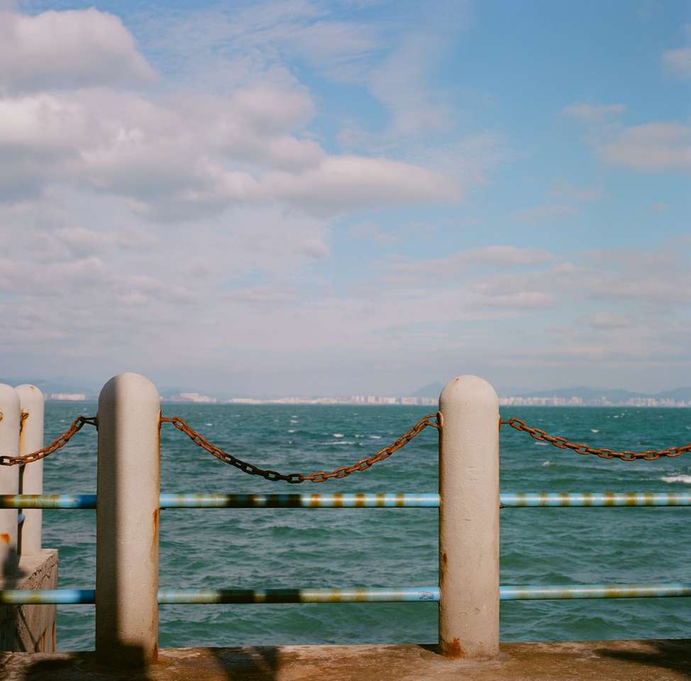 коричневый деревянный док на синем море под белыми облаками пазл онлайн