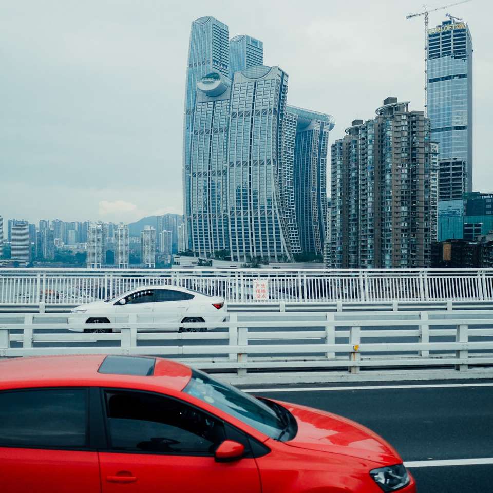 červené auto na silnici poblíž městských budov během dne skládačky online