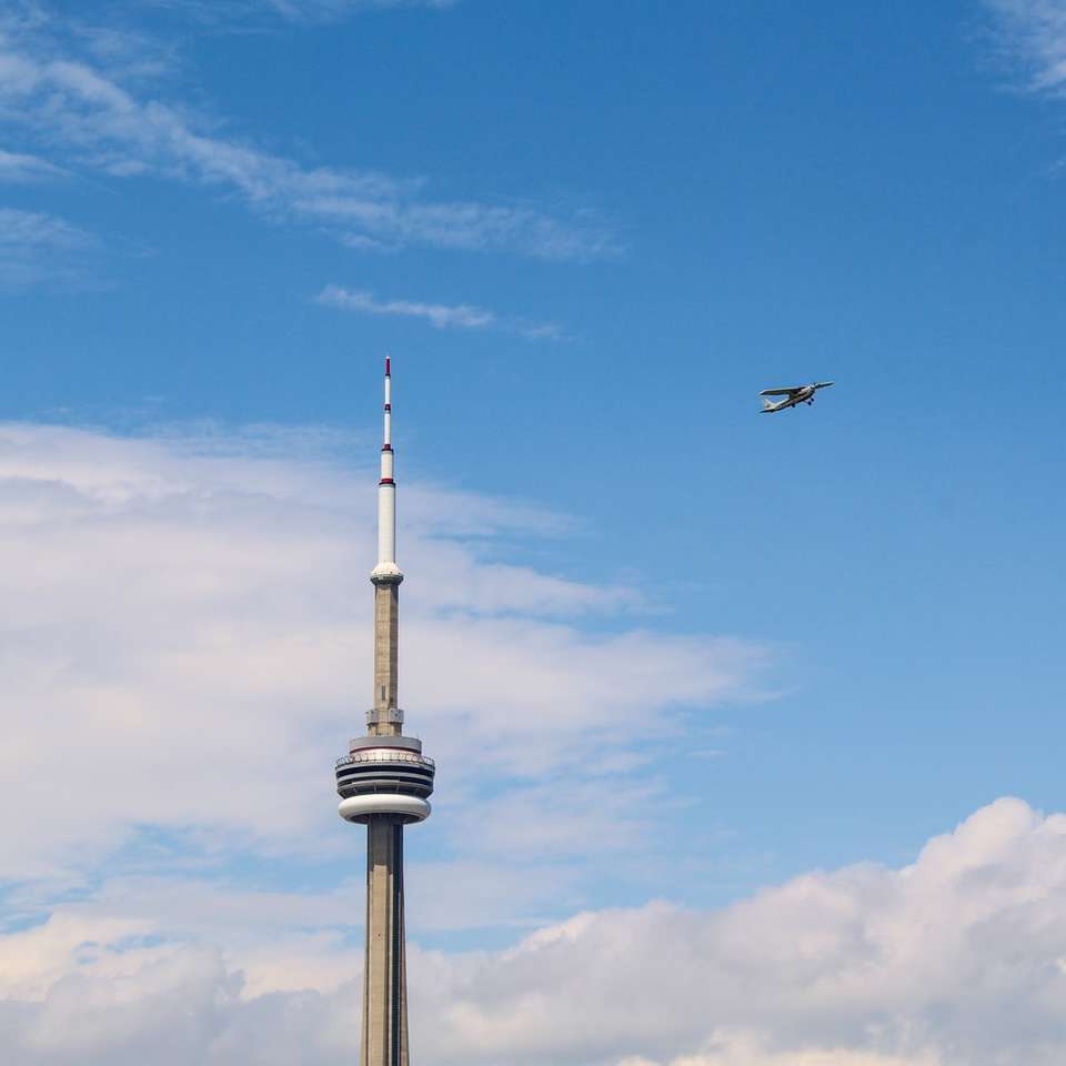 черна птица, летяща над бяла кула под синьо небе онлайн пъзел