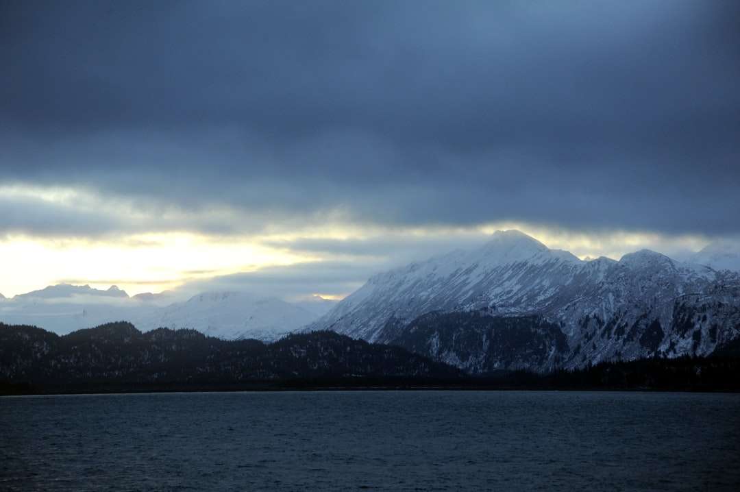 заснежена планина в близост до водоема през деня онлайн пъзел