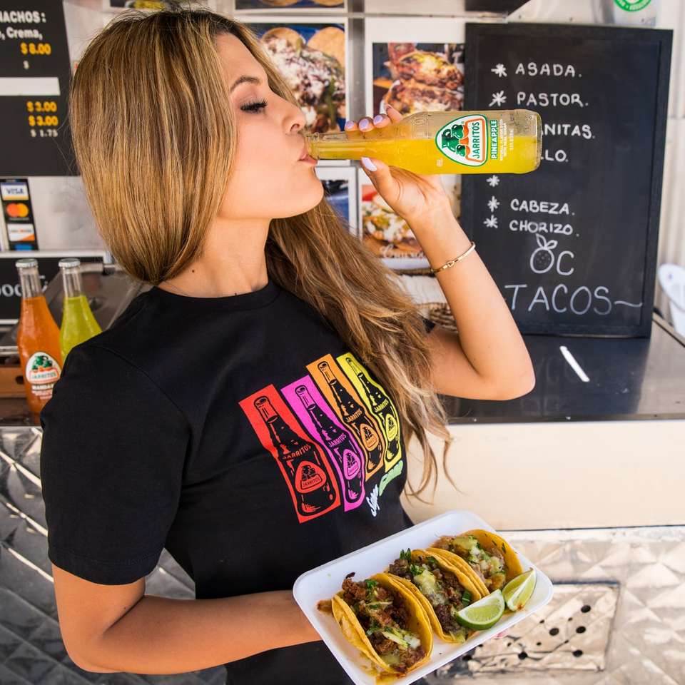 Femme en t-shirt à col rond noir mangeant un hamburger puzzle en ligne