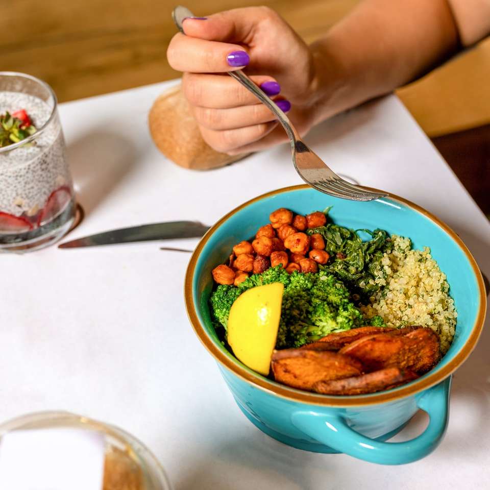 Persona sosteniendo una cuchara con comida en un tazón de cerámica azul rompecabezas en línea
