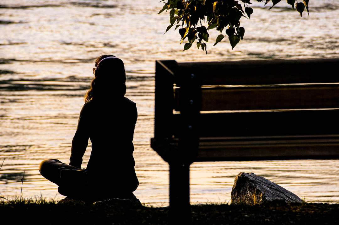 Silhouette der Person, die auf Bank nahe dem Gewässer sitzt Online-Puzzle