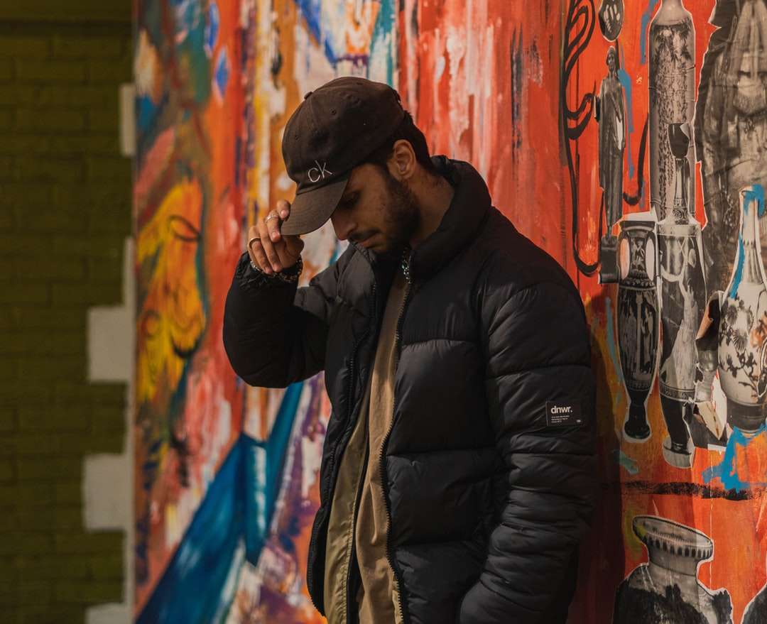 мъж в черно яке, стоящ до стената с графити онлайн пъзел