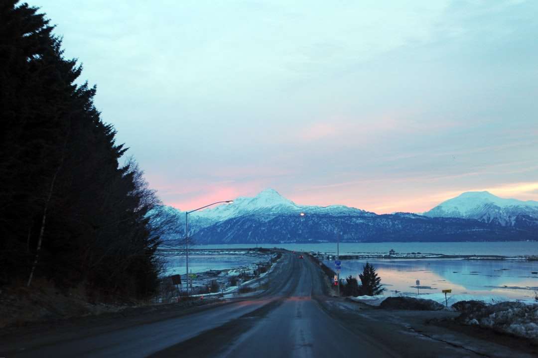 svart asfaltväg nära snötäckt berg under dagtid Pussel online